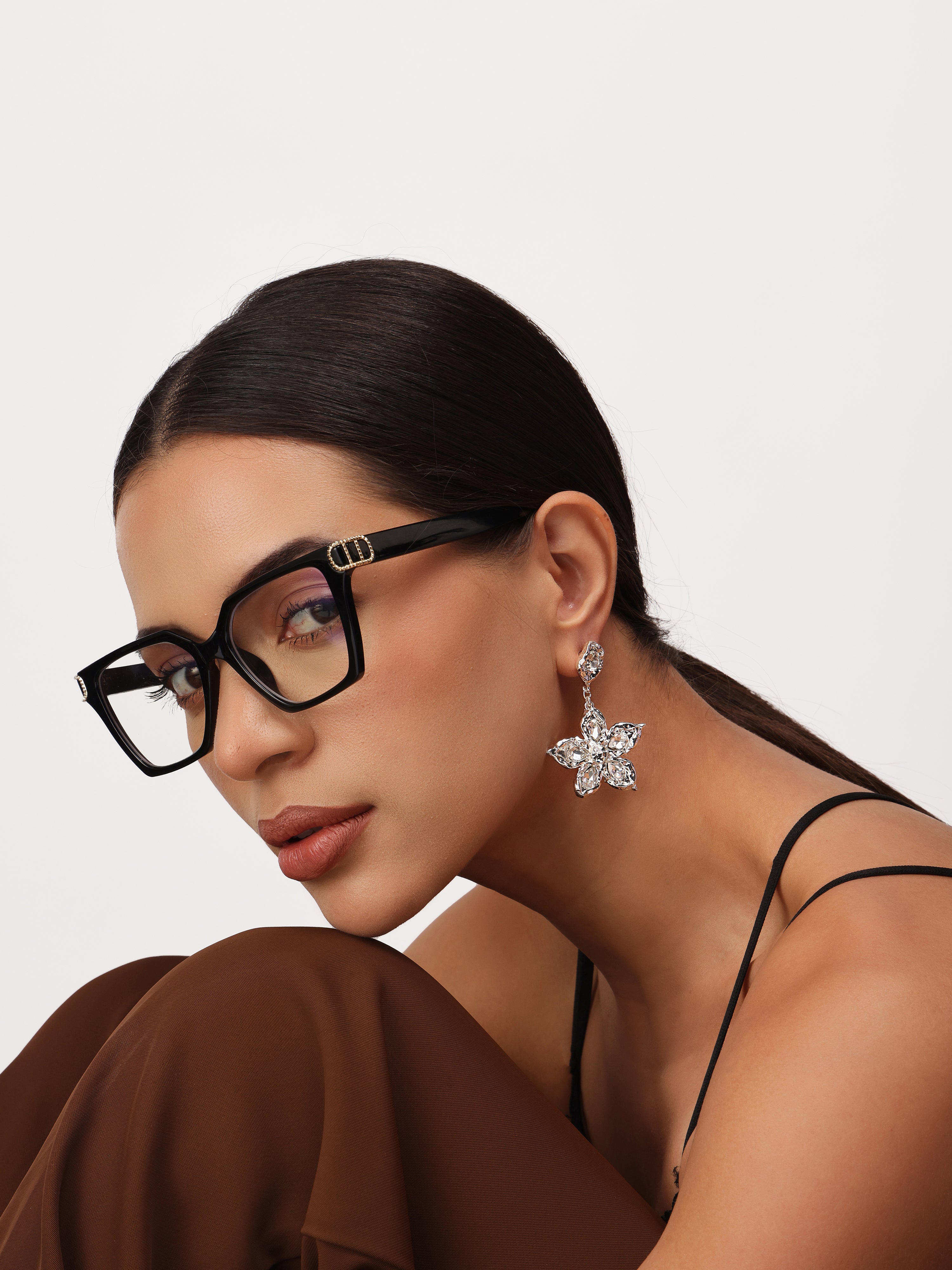 Woman wearing real silver micron plated flower drop earrings on a neutral background